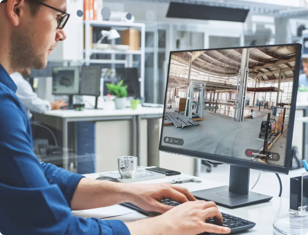 Person am Monitor betrachtet den digitalen Zwilling einer Produktionshalle in Matterport